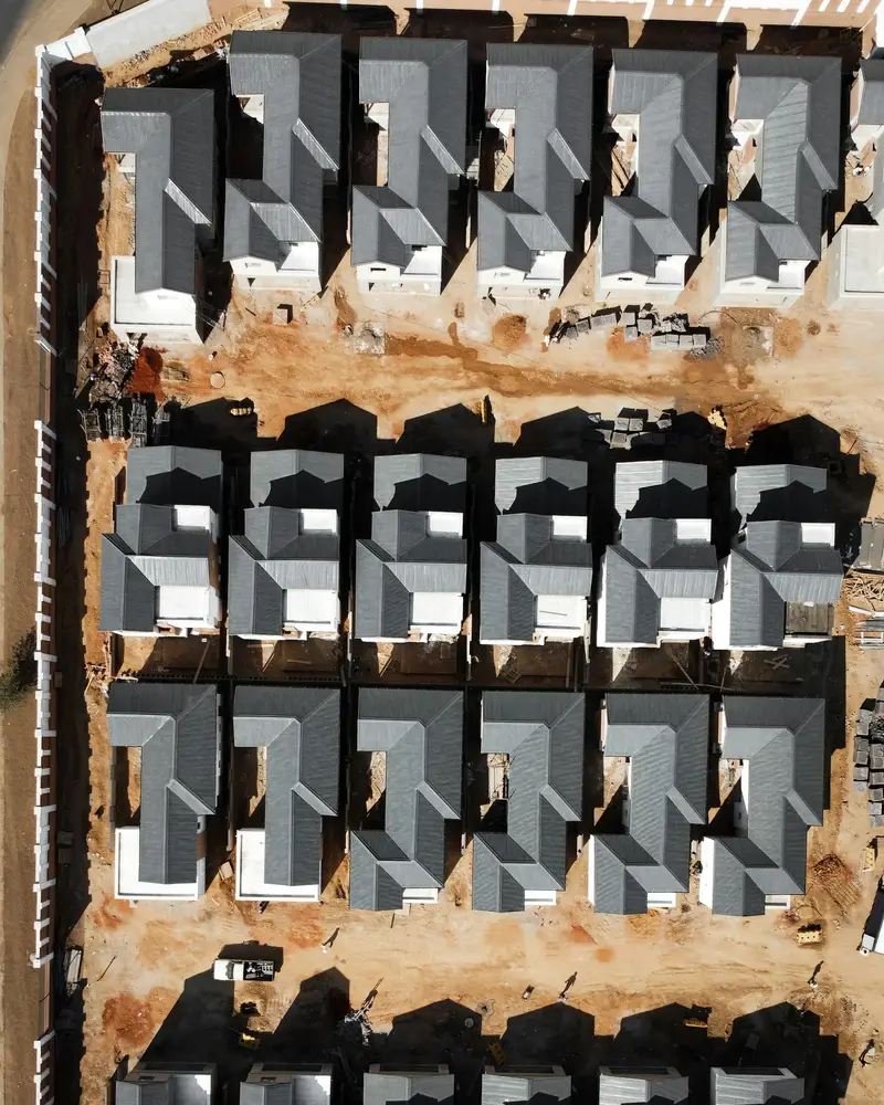 Aerial view of a housing estate under construction with rows of grey roofs